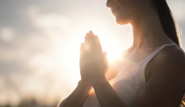 Woman praying for her wife's health, bathed in soft, hopeful light.